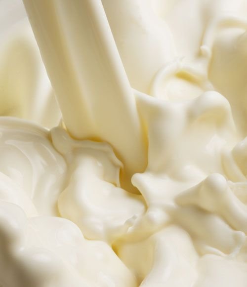 Cream being poured, creating smooth swirls. Close-up of rich, creamy texture suitable for food and dairy content.