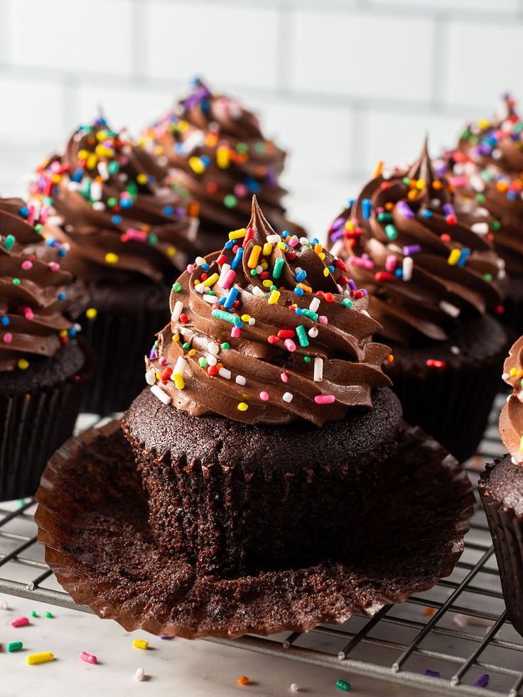 Rich chocolate cupcakes adorned with creamy frosting and colorful sprinkles, perfectly displayed on a cooling rack.