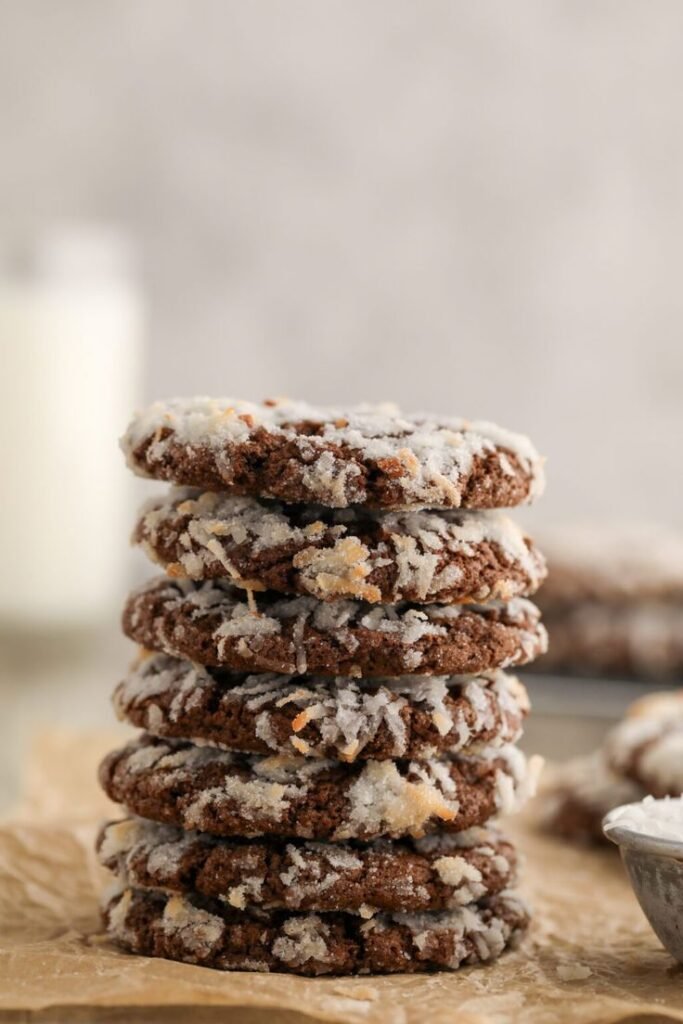 Stack of chocolate coconut cookies on parchment paper, with a blurred background, perfect for a dessert blog.