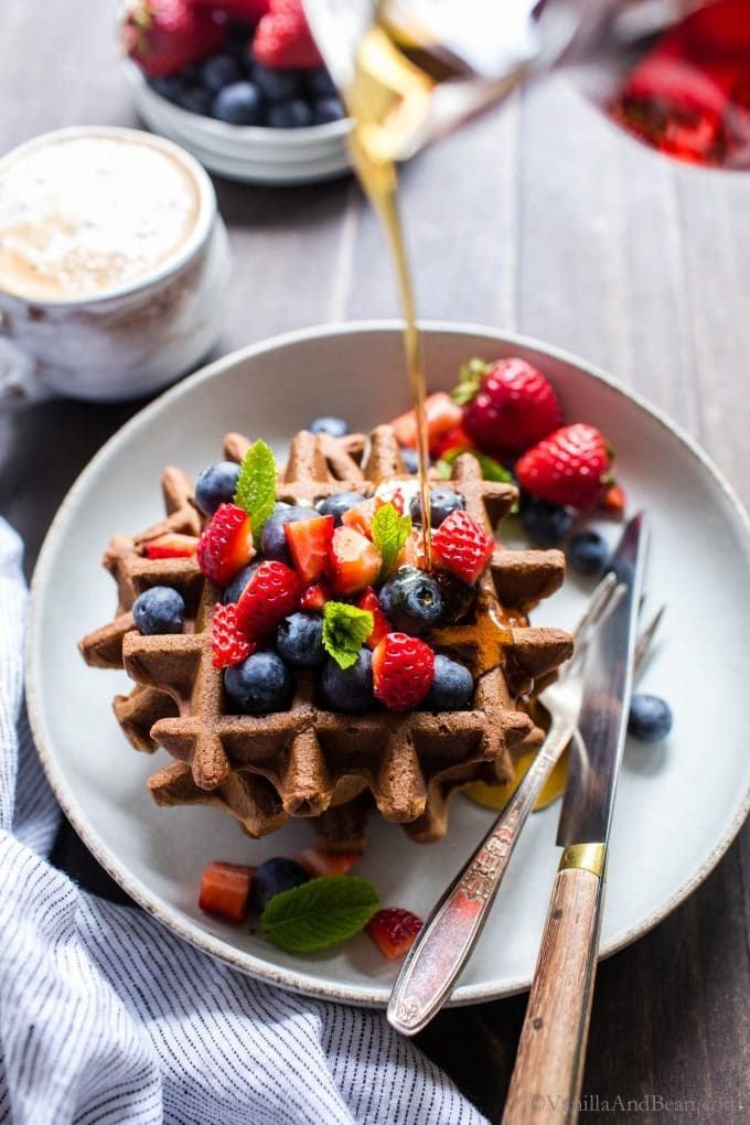 Delicious waffles with fresh berries and maple syrup, served with coffee for a perfect breakfast.