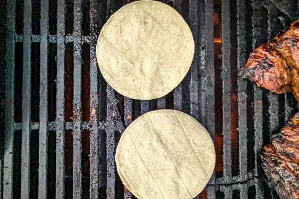 Grilling tortillas and meat on a barbecue for a tasty outdoor meal.