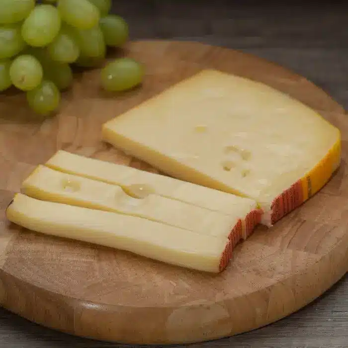 Cheese slices and grapes on a wooden board, perfect for a gourmet snack or party platter.