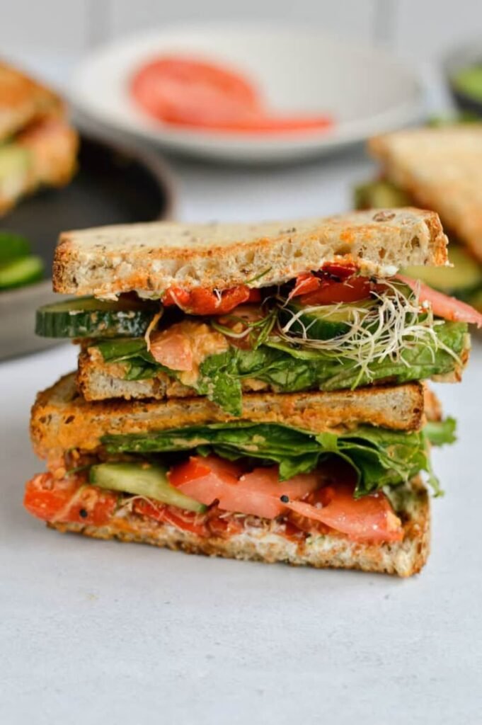 Delicious veggie sandwich with tomato, cucumber, and greens stacked high on whole grain bread.