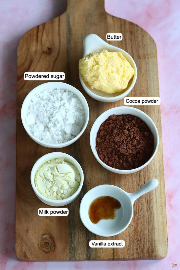 Ingredients on a board: butter, cocoa powder, powdered sugar, milk powder, vanilla extract; perfect for baking.