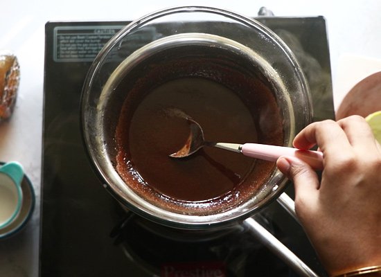 Stirring melted chocolate in a double boiler on a stovetop for baking or dessert preparation.