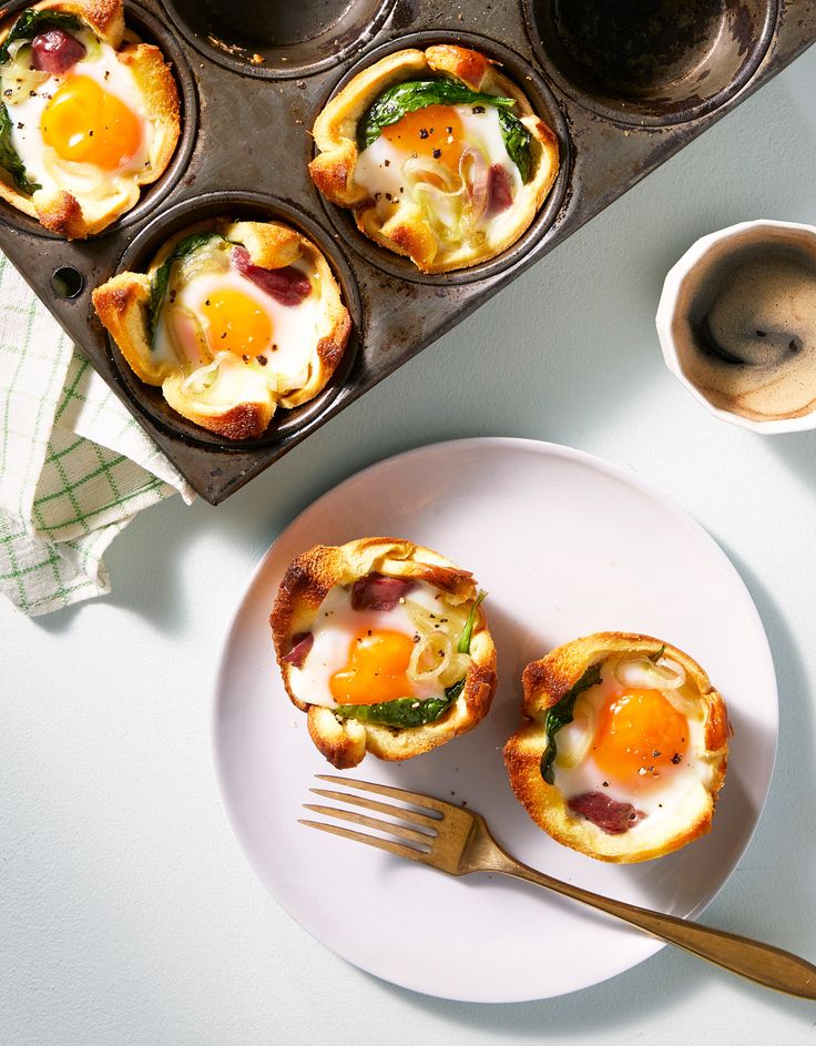 Baked egg and spinach cups in a muffin tin and served on a plate with a fork, perfect for a savory breakfast.