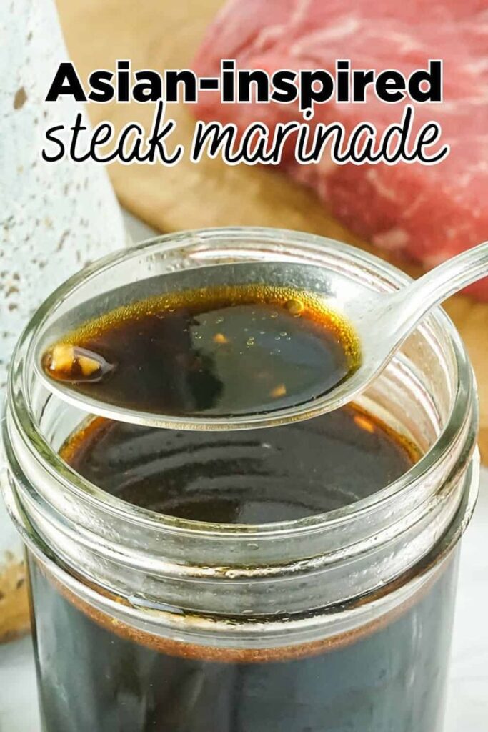 Jar of Asian-inspired steak marinade with a spoon, next to a piece of raw beef.