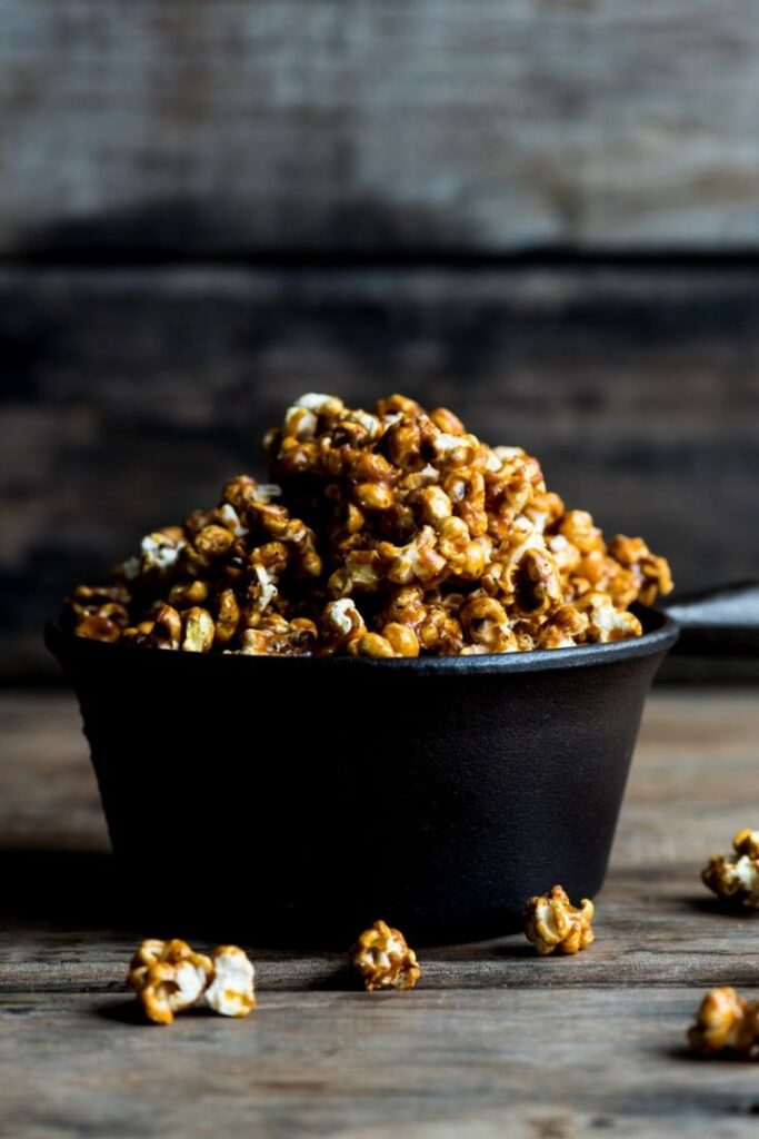 Caramel popcorn in a bowl on a rustic wooden table, perfect snack for movie nights or parties.