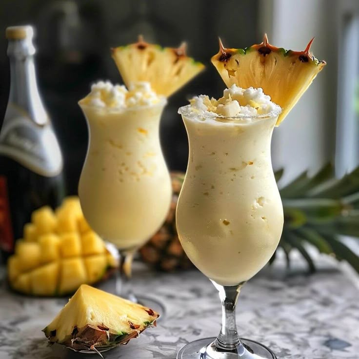 Refreshing pineapple mango smoothie in stylish glasses, garnished with pineapple slice, perfect summer drink.