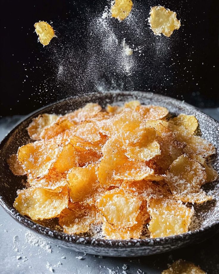 Crispy potato chips sprinkled with grated cheese in a bowl, showcasing savory snack perfection.