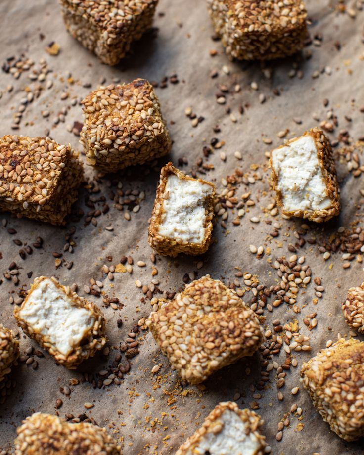 Crispy sesame-crusted tofu cubes on parchment paper, perfect for a vegan snack or appetizer.