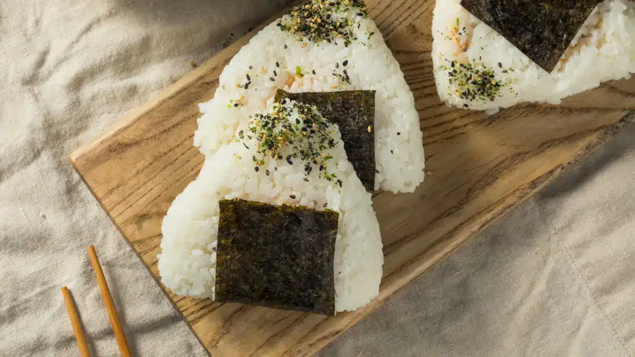 Onigiri rice balls with seaweed and sesame seasoning on a wooden board. Japanese cuisine.