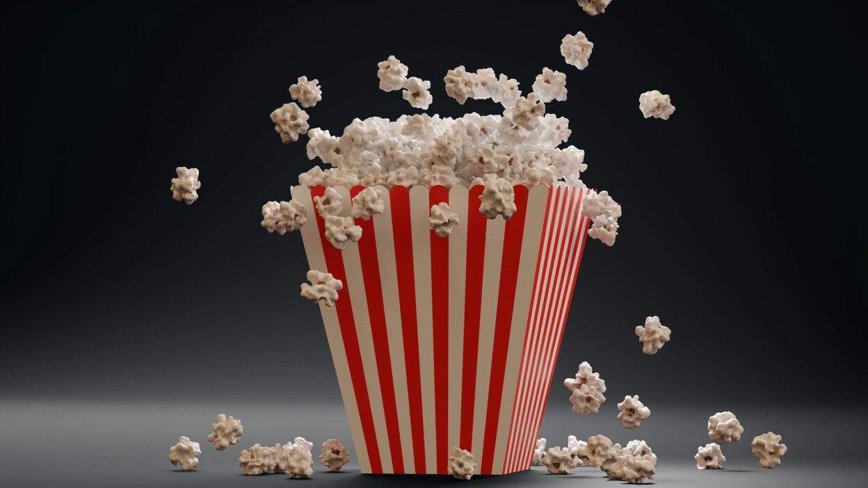 Overflowing popcorn box with red stripes on a dark background.