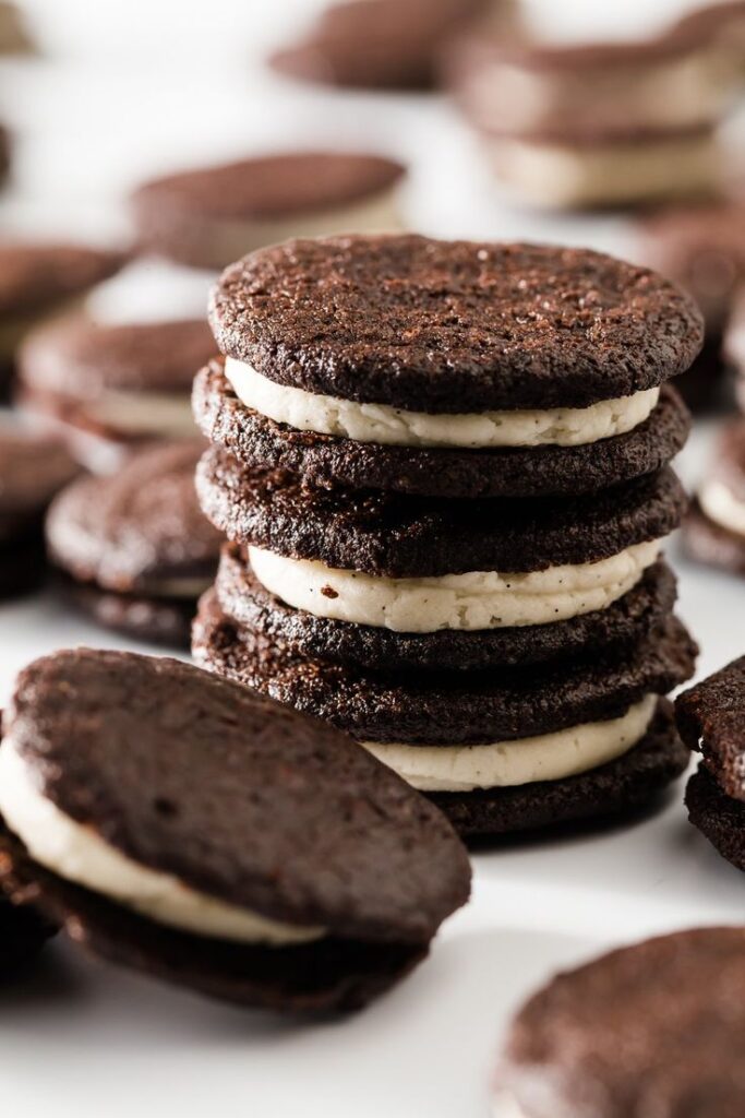 Stack of chocolate sandwich cookies with creamy filling, arranged on a white background.