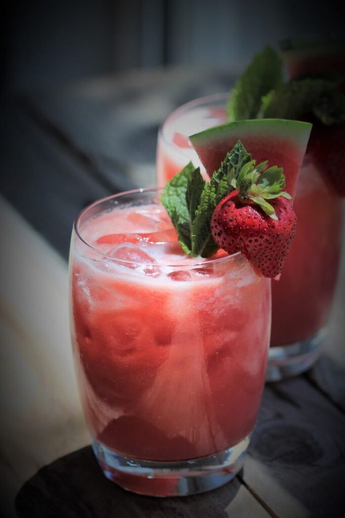 Refreshing watermelon strawberry drink garnished with fresh mint, served in a glass with ice cubes.