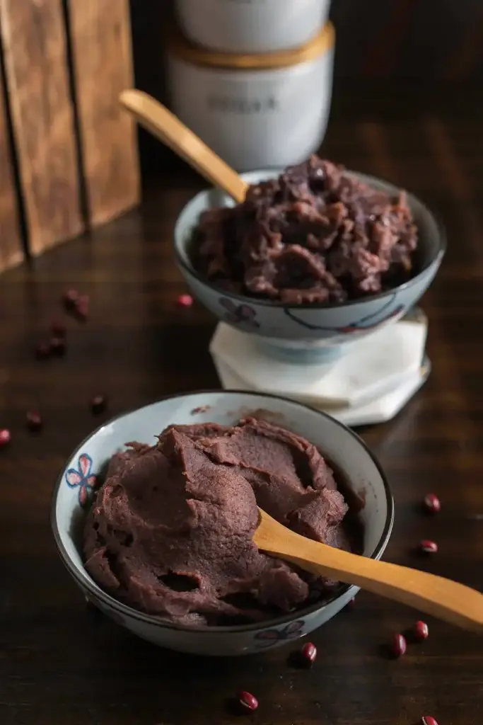 Bowls of homemade red bean paste with wooden spoons, perfect for Asian desserts.
