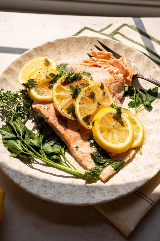 Plate of lemon-herb salmon garnished with fresh parsley, ready to serve.