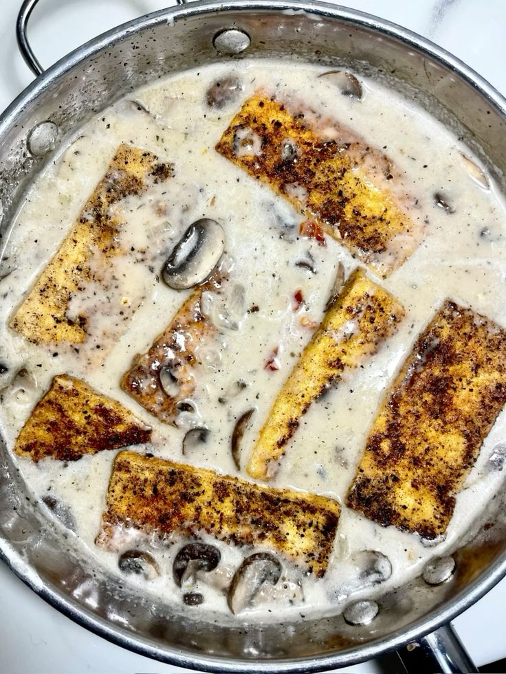 Creamy mushroom chicken dish in a skillet, showcasing crispy breading and rich savory sauce.