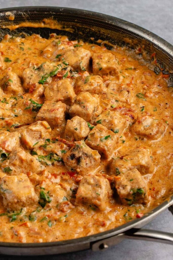Creamy tofu curry with herbs in a skillet, rich in spices and flavor, perfect for vegetarian recipes.