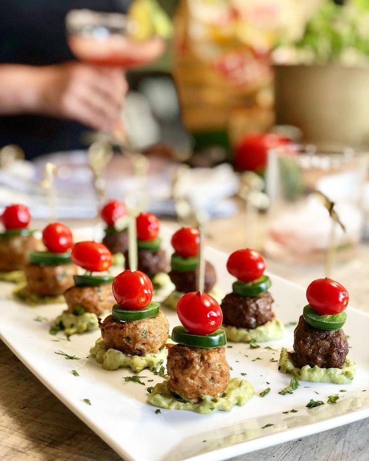Mini meatball skewers with cherry tomatoes and jalapeños on a platter, perfect for party appetizers.