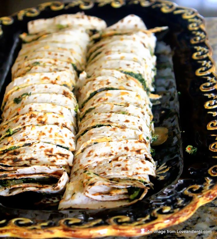 Sliced, grilled pinwheel sandwiches filled with greens on a decorative platter, ready to serve.