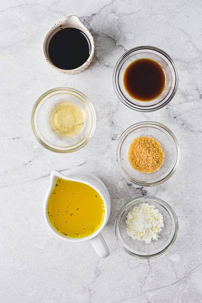 Various sauces and spices in small bowls on a marble surface, ideal for gourmet cooking and meal preparation.