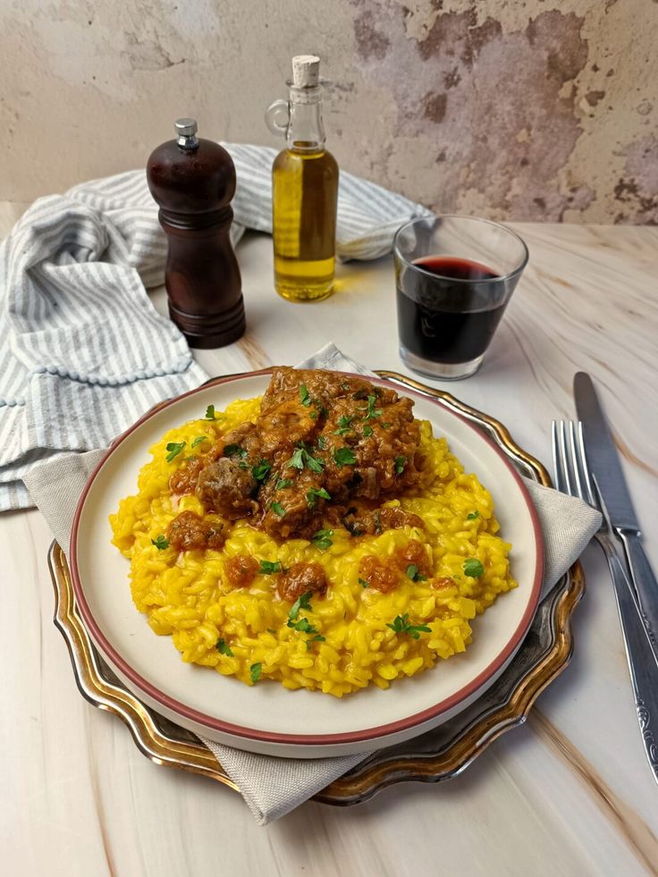 Saffron risotto topped with hearty stew, served with olive oil and red wine on a rustic table setting.