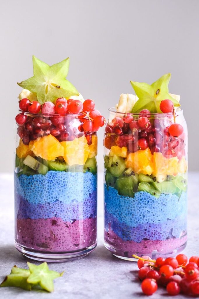 Colorful layered chia pudding with fresh fruit toppings in glass jars. Healthy and vibrant breakfast option.