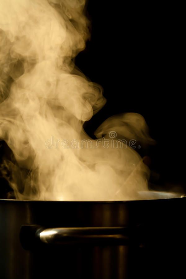 Steam rising from a boiling pot against a dark background, showing the power and beauty of cooking heat in motion.