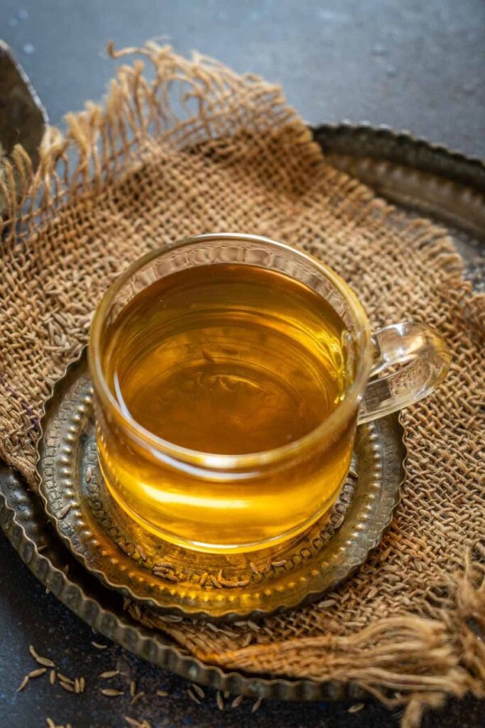 Glass of herbal tea on a rustic tray with burlap, showcasing a warm ambiance and natural ingredients.