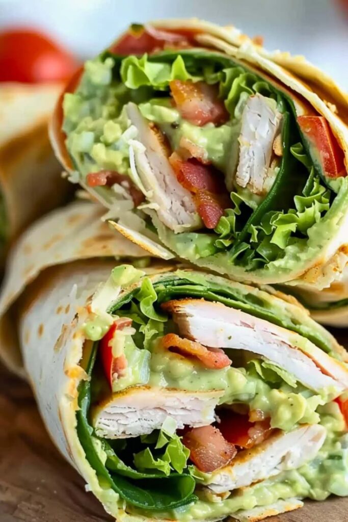 Fresh turkey avocado wrap with lettuce, tomato, and bacon, showcasing healthy and delicious ingredients.