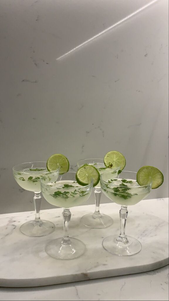 Chilled cocktails garnished with lime slices and mint on a marble platter, perfect for a refreshing summer drink.