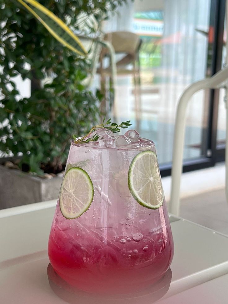 Refreshing pink cocktail with lime slices and ice in a cafe setting. Perfect summer drink.