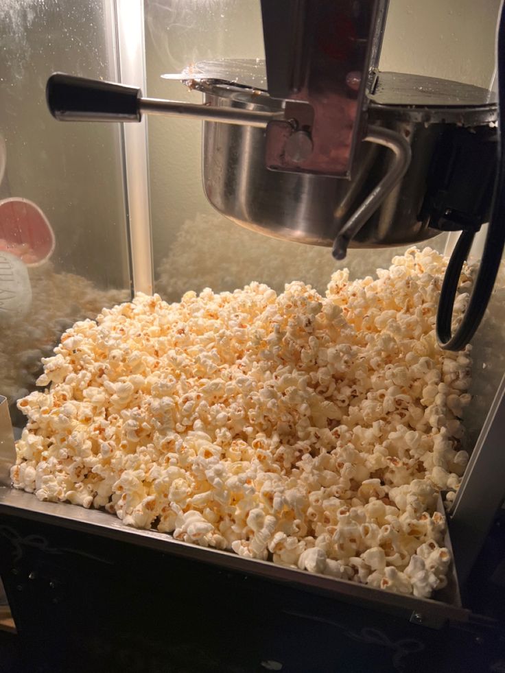 Popcorn machine overflowing with fresh popcorn in warm light. Perfect for movie night or events.