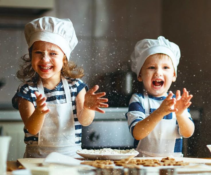 Children in chef hats joyfully baking and playing with flour in a kitchen.