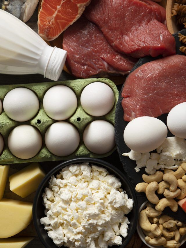 Assorted protein-rich foods: eggs, meat, cheese, salmon, cashews, milk, and cottage cheese displayed together.