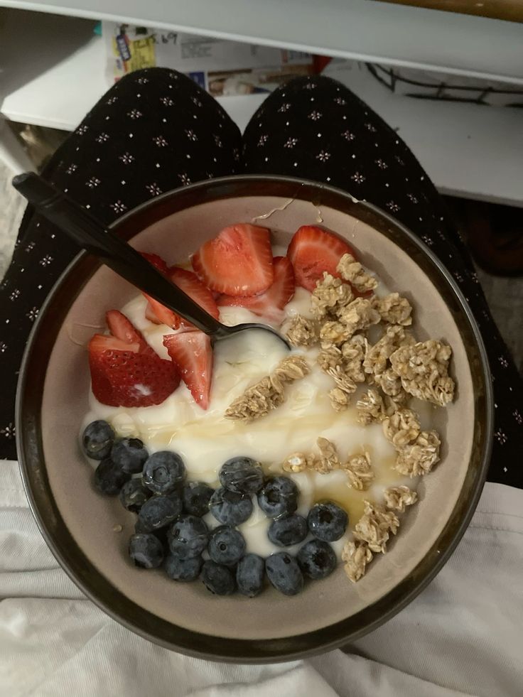 Bowl of yogurt topped with fresh strawberries, blueberries, and granola, perfect for a healthy breakfast.
