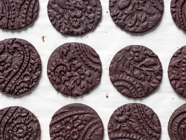 Decorative chocolate cookies on parchment paper, featuring intricate patterns and rich texture. Perfect for desserts.