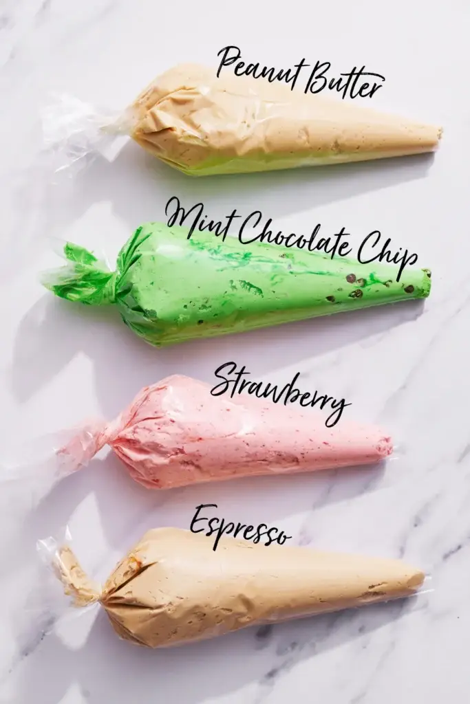 Assorted frosting bags labeled: Peanut Butter, Mint Chocolate Chip, Strawberry, Espresso, on a marble surface.