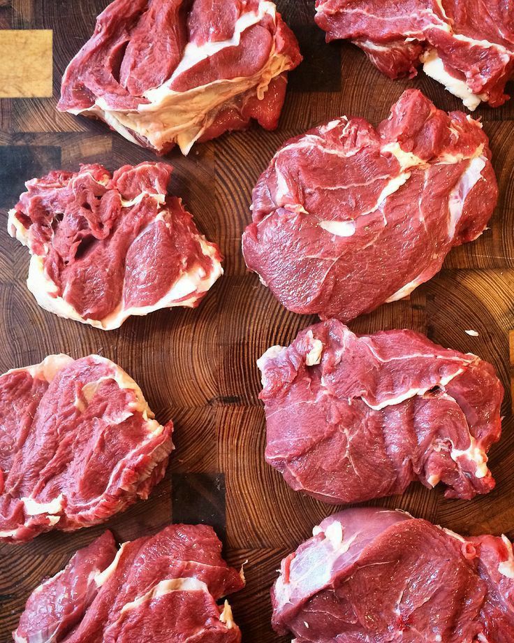 Raw steaks on a wooden cutting board, ready for cooking preparation.