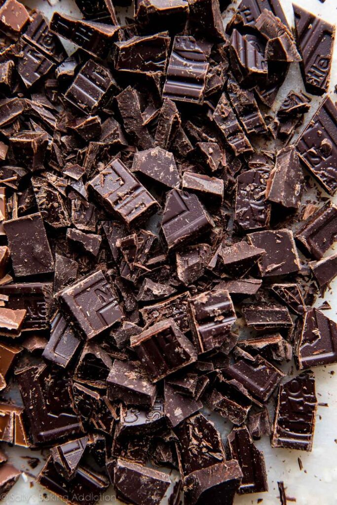 Chopped dark chocolate chunks scattered on a table, ready for baking or snacking.