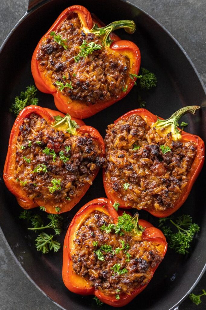 Delicious baked stuffed bell peppers filled with seasoned beef and rice, garnished with fresh parsley.