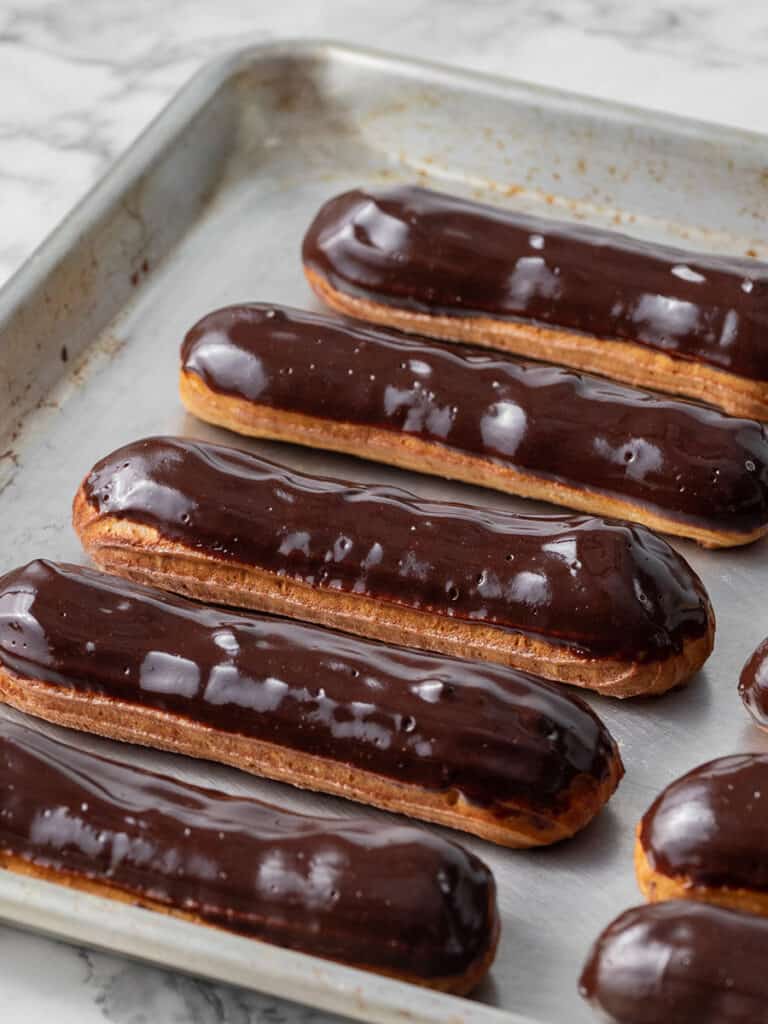 Chocolate glazed eclairs on a baking tray, perfect French pastry dessert.