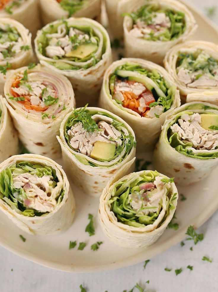 Fresh tortilla wraps with chicken, avocado, and vegetables on a white plate, garnished with herbs. Perfect for lunch!