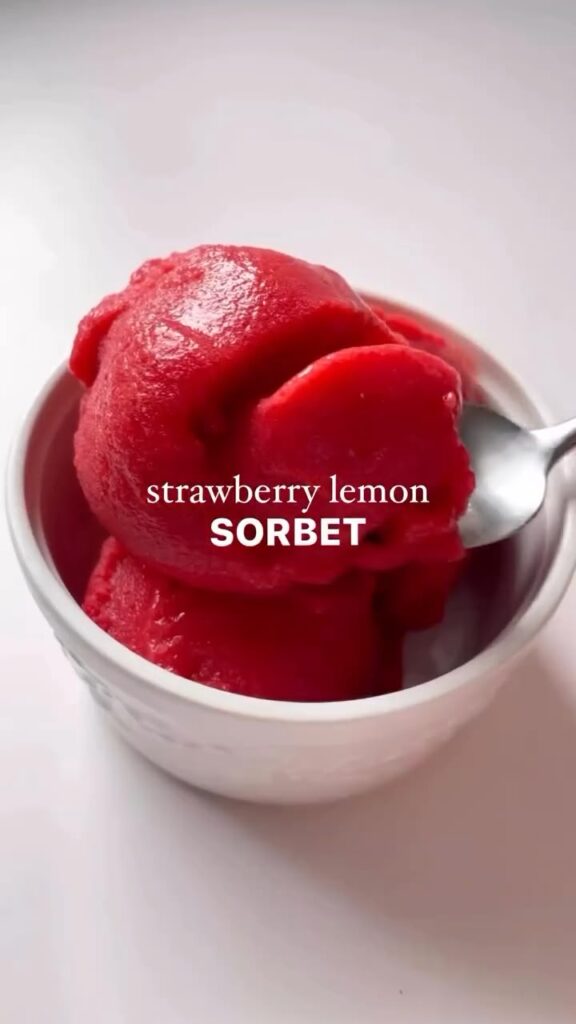 Strawberry lemon sorbet in a white bowl with spoon, refreshing summer dessert.