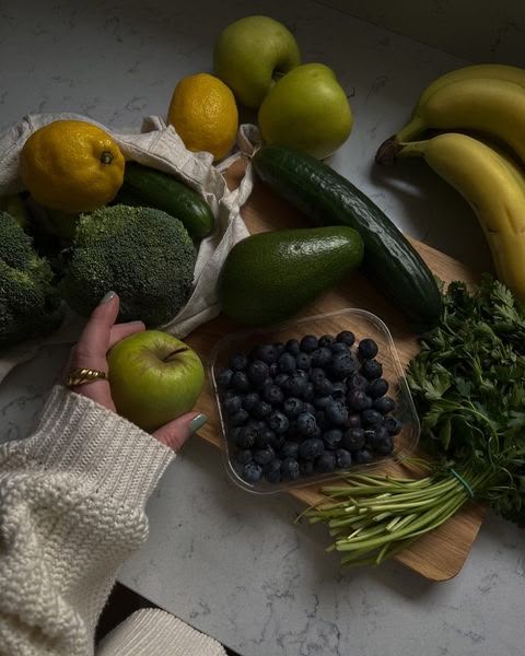 Fresh fruits and vegetables on a countertop, featuring bananas, blueberries, cucumbers, and broccoli.