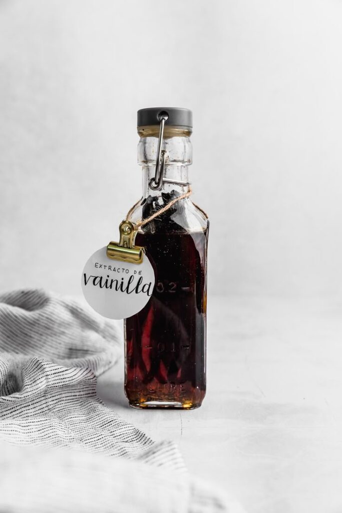 Glass bottle of vanilla extract with label and grey background.