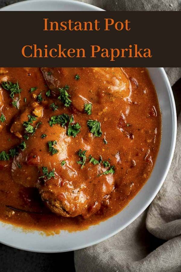 Bowl of Instant Pot chicken paprika garnished with fresh parsley, showcasing rich sauce and vibrant color.