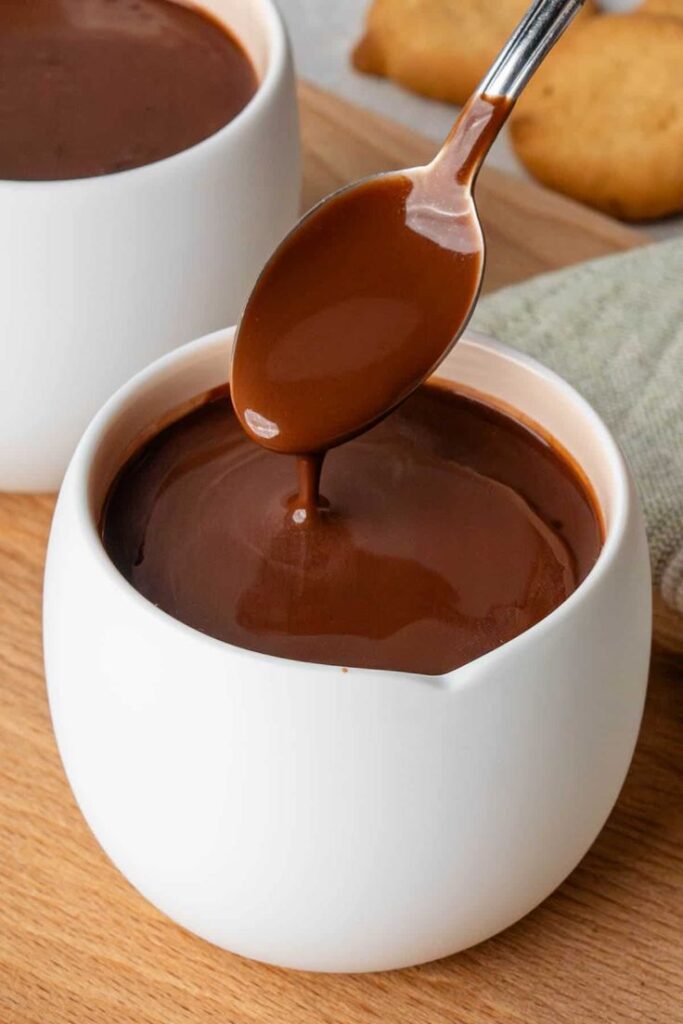 Rich hot chocolate in a white cup with a spoon, perfect cozy treat.