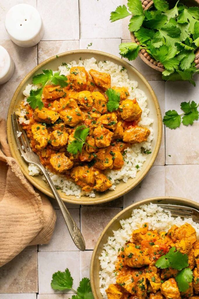 Delicious chicken curry served on rice with fresh cilantro garnish on a rustic table setting.